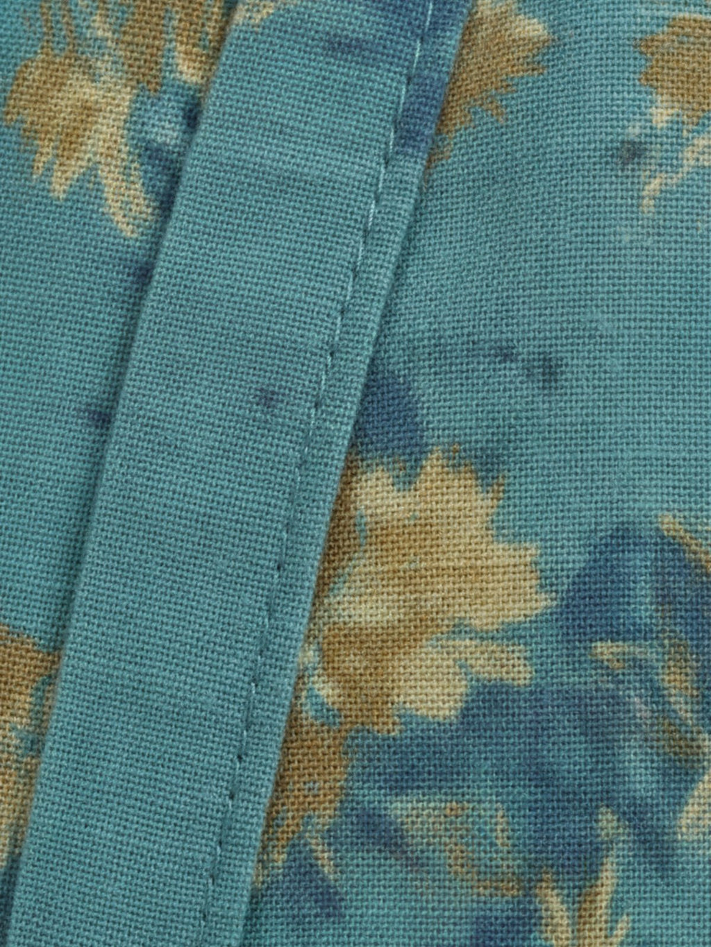 Détail du tissu turquoise à motifs botaniques du peignoir Kasane