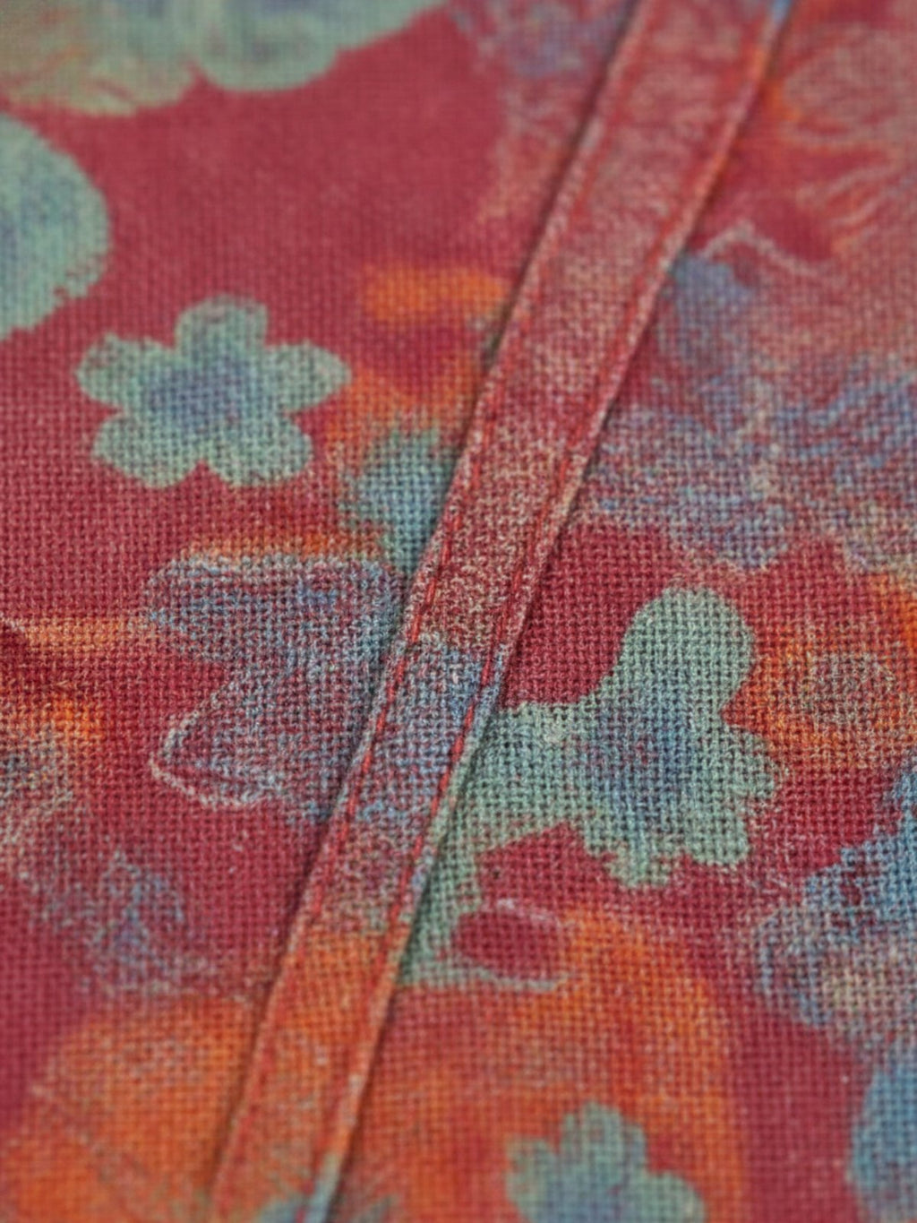 Détail du tissu rouge à motifs floraux et de la poche du peignoir Saki